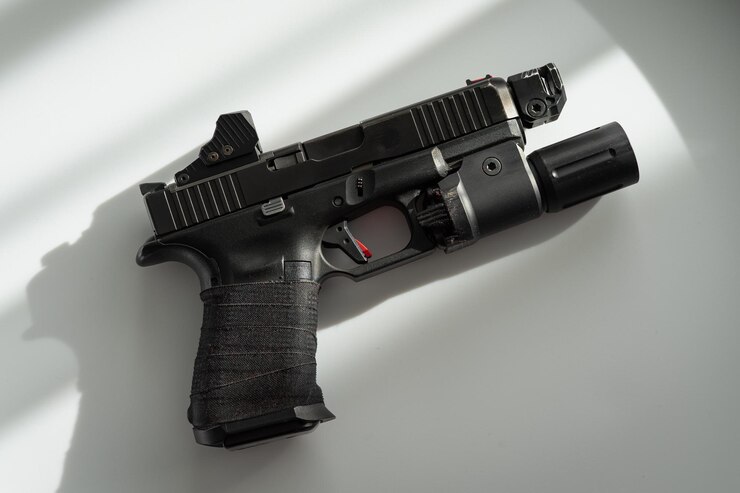 A hand gun mounted with flashlight and red dot sight.